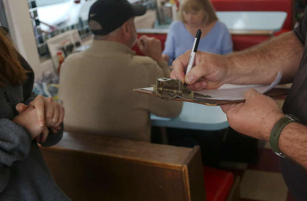 Dave Johnson writes down names and phone numbers of customers